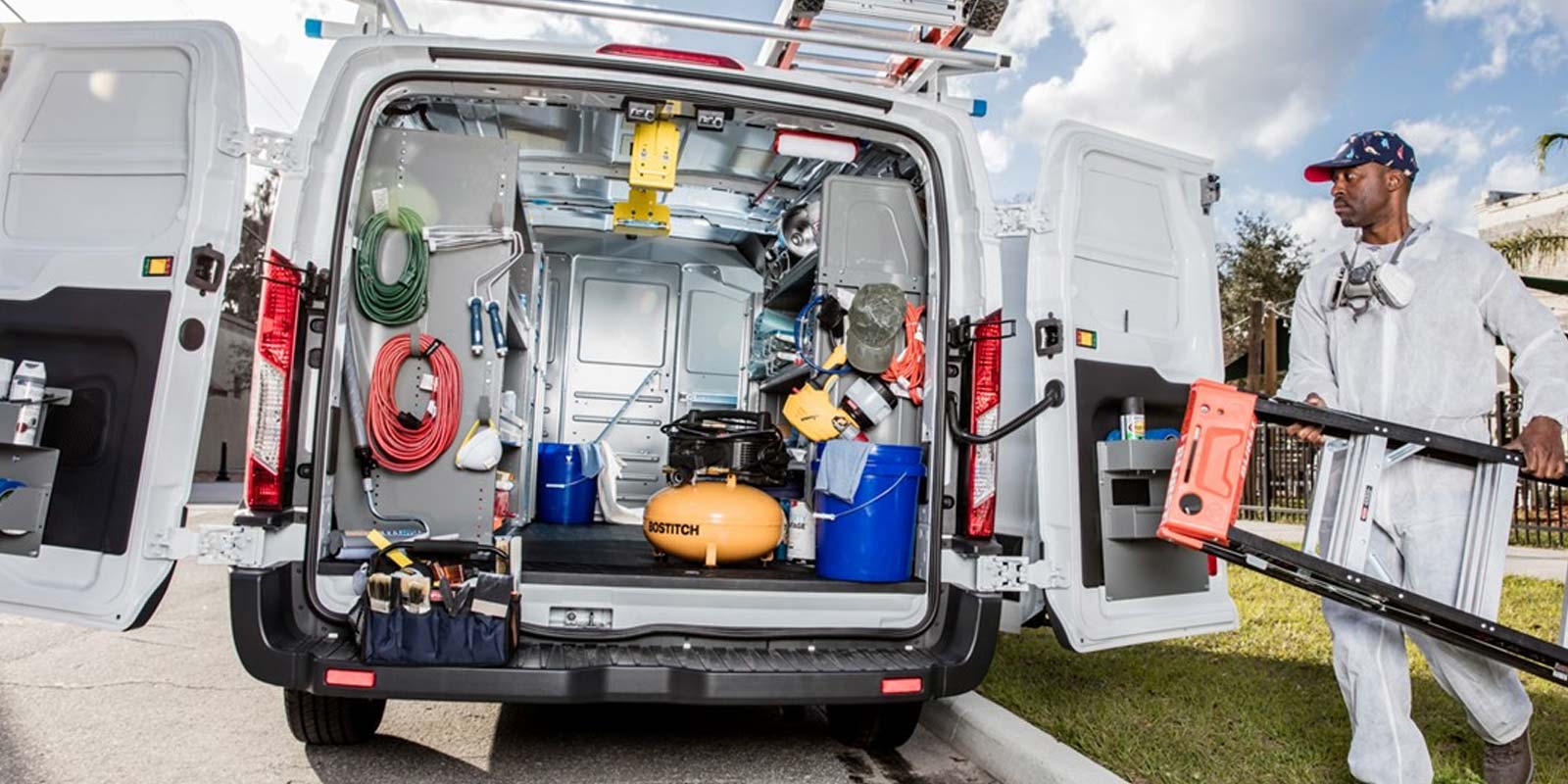 Worker at a residential construction site with a fully upfit NV cargo van.